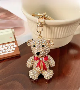 Close-up of sparkling crystal teddy bear keychain with a red bow on a wooden surface