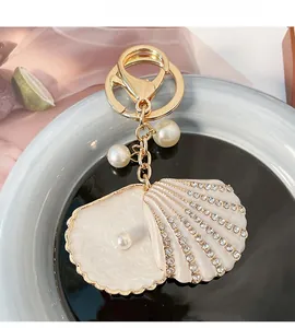 Detail of a shell-shaped gold keychain featuring sparkling rhinestones and elegant pearls