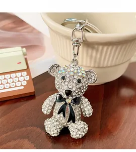 Detailed view of rhinestone bear keychain with black bow hanging on a white ceramic cup