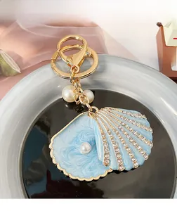 Detail of blue shell keychain with rhinestones and white pearls on golden base