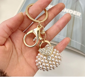 Detailed view of pearl handbag keychain with crystal accents and golden clasp hardware