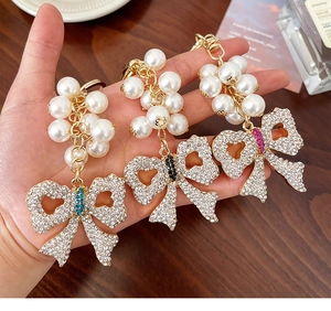 Macro shot of handmade pearl and rhinestone bow keychains in blue, black and pink