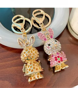Detail of crystal-encrusted rabbit keychain and gold mesh bunny charm on a dark wood desk