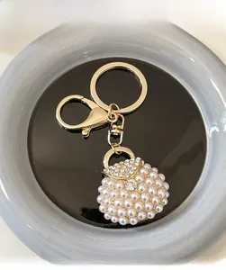 Close-up of golden handbag keychain with sparkling pearls and rhinestones on blue plate