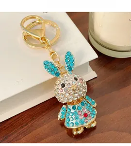 Close-up of golden bunny keychain with colorful rhinestones on a white book surface