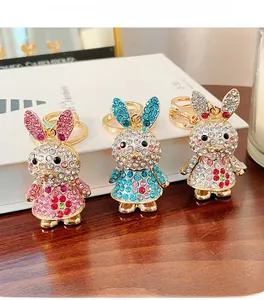 Detailed view of rhinestone bunny keychains in pink, blue and silver on wooden desk