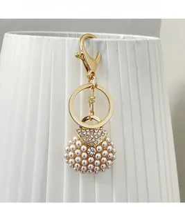 Close-up of pearl and rhinestone luxury handbag charm with golden metal lobster clasp