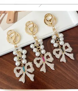 Detail of handmade pearl keychains with crystal-studded bow charms in gold metal finish