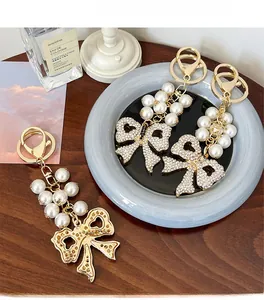 Detail of pearl bow keychain with sparkling rhinestones and elegant gold metal clasp