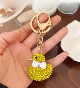 Detailed view of yellow rhinestone duck keychain with gold hardware and white bow decoration