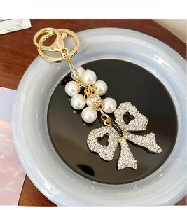Close-up of pearl bow keychain with pavé rhinestones and heart-shaped hollow design