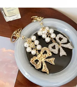 Detailed close-up of handmade pearl bow keychain charms on a ceramic plate tray