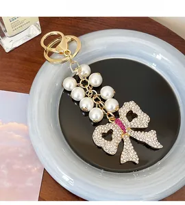 Detailed view of handmade pearl keychain with crystal-encrusted bow pendant and gold clasp