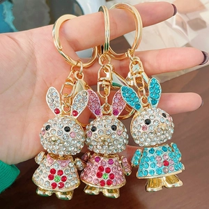 Handheld view of sparkling rabbit keychains with colorful rhinestones in three colors