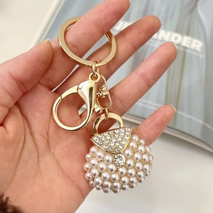 Elegant gold keychain with pearl-encrusted handbag charm and sparkling rhinestones