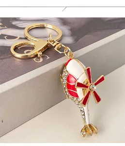 Close-up of golden helicopter keychain with sparkling crystals and red enamel detailing