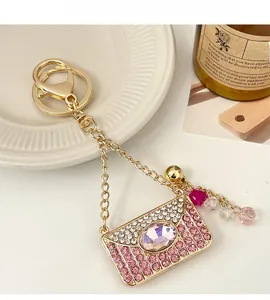 Détail porte-clés sac à main en cristal avec pierres roses, clochette d'or et perles