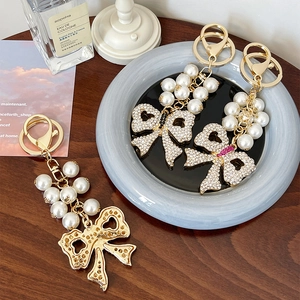 Sparkling rhinestone bow keychain with pearls on a vintage wooden table setting