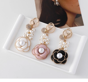Detail view of camellia pearl keychains in white pink and black with gold alloy