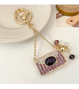 Détail du porte-clés enveloppe orné de gemmes violettes et de cristaux étincelants