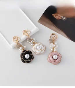 Detailed view of camellia flower keychain with elegant pearls and sparkling gold hardware