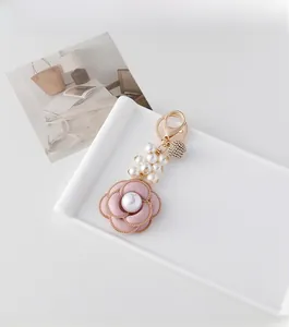 Detailed close-up of a pink camellia charm with pearls and rhinestone ball for handbags