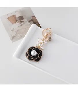 Detail of French-style black camellia pearl keychain with gold chain and crystal ball