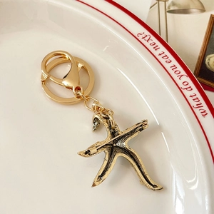 Vintage gold starfish keychain and brooch with crystals on a white ceramic plate