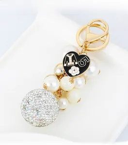 Detail of luxury keychain with number 5 heart charm, white pearls and crystal ball