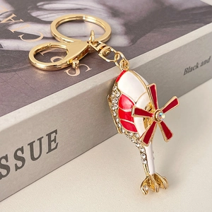 Red and white helicopter keychain with crystals and gold plating on a book