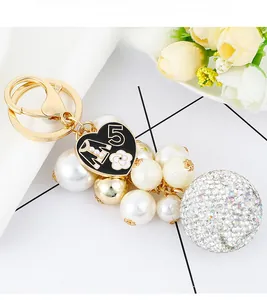 Detailed close-up of gold keychain with crystal rhinestone ball and pearl charms