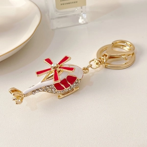 Golden helicopter keychain with red white enamel and crystals on textured background