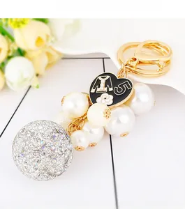 Detail of a luxury keychain with rhinestone ball, white pearls and gold metal accents