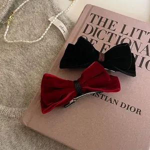 Set of two vintage velvet bow hair clips in classic black and red on a pink book