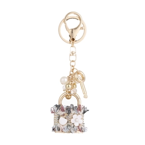 Elegant woven mini bag keychain with white enamel flower, pearls and gold hardware