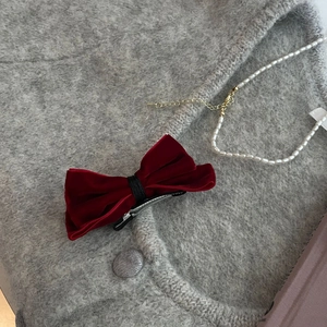 Elegant vintage red velvet bow hair clip with silver metal duckbill clip on gray sweater