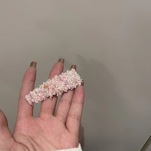Detailed macro of pink and white tweed rectangular hair clip with gold thread accents