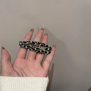 Close-up of black and gold tweed woven hair clip held in hand for detail