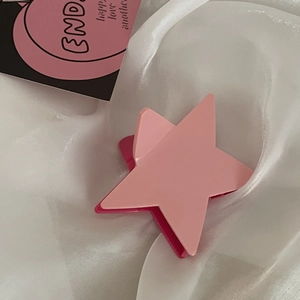 Dettaglio molletta capelli stella Y2K rosa con texture opaca su seta bianca morbida