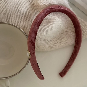 Elegant wine red velvet headband with a white pearl and gold base on a soft background