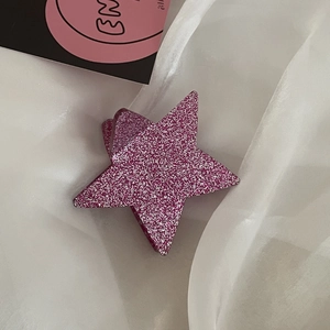 Macro di una clip per capelli y2k a stella rosa con finitura glitterata e trama acetato