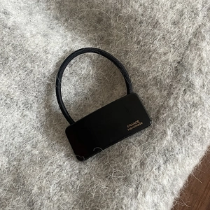 Detail of black elastic hair tie with rectangular handmade acrylic plate on mohair