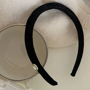 Detail of a velvet headband with a round white pearl set in a gold metallic base
