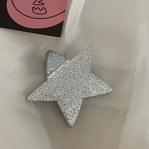 Dettaglio della molletta per capelli a stella glitter argento su fondo di tulle bianco