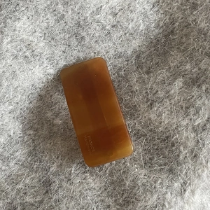 Detail of amber acetate hair clip with France Handmade gold lettering on grey fabric