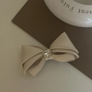 Pince à cheveux élégante en satin crème avec un ornement central en strass en forme de cœur