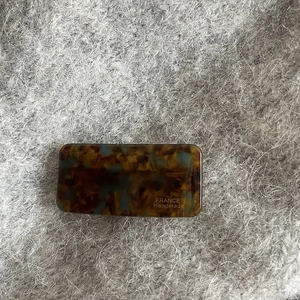 Detail of a rectangular acetate hair clip with vintage tortoiseshell and teal patterns