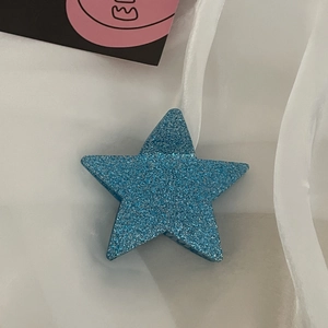Dettaglio macro della molletta per capelli a stella glitter blu con estetica trendy Y2K