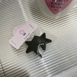 Nahaufnahme der schwarzen Stern-Haarklammer auf einer rosa herzförmigen Displaykarte