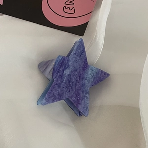 Dettaglio macro del fermaglio a stella Y2K con texture nebulosa viola e glitter argento